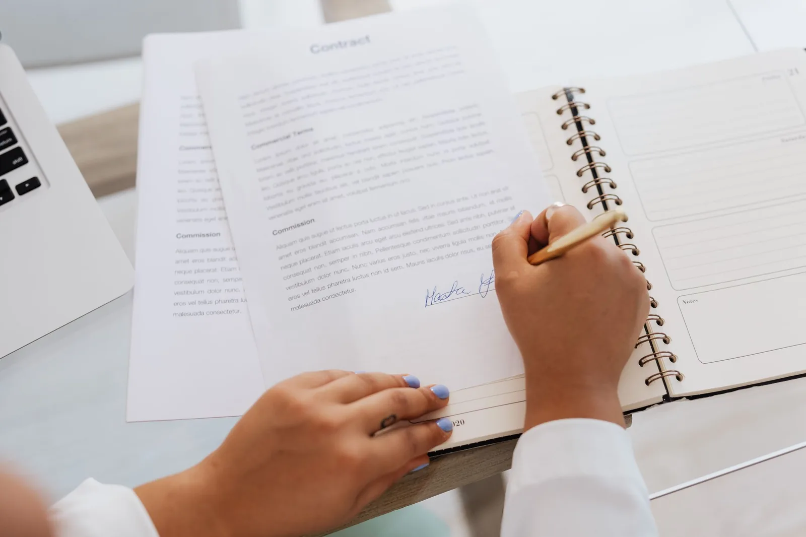 Revisione e firma di un documento accanto a un portatile